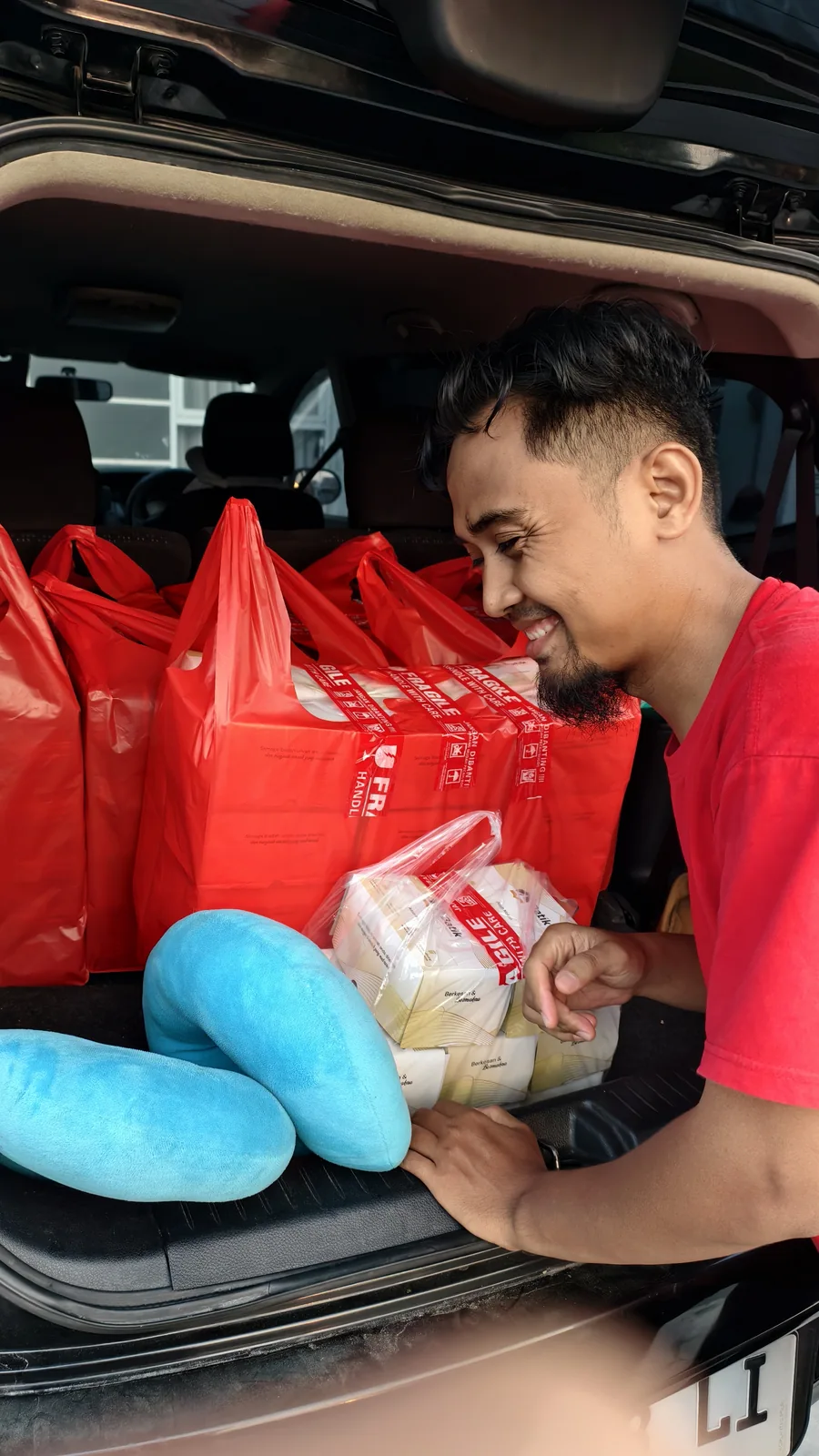Dokumentasi seseorang bersama tas pesanan di dekat kendaraan